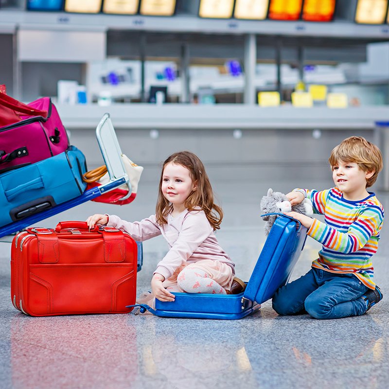two little kids, boy and girl going on vacations trip with suitcase at airport