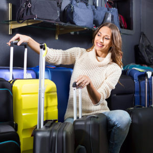 Cliente positive et joyeuse choisissant une valise de voyage dans un magasin