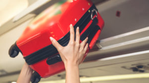 cabin crew lift luggage bag in airplane